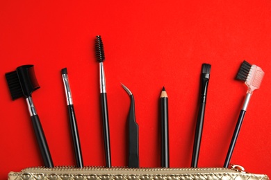 Photo of Set of professional eyebrow tools on red background, flat lay