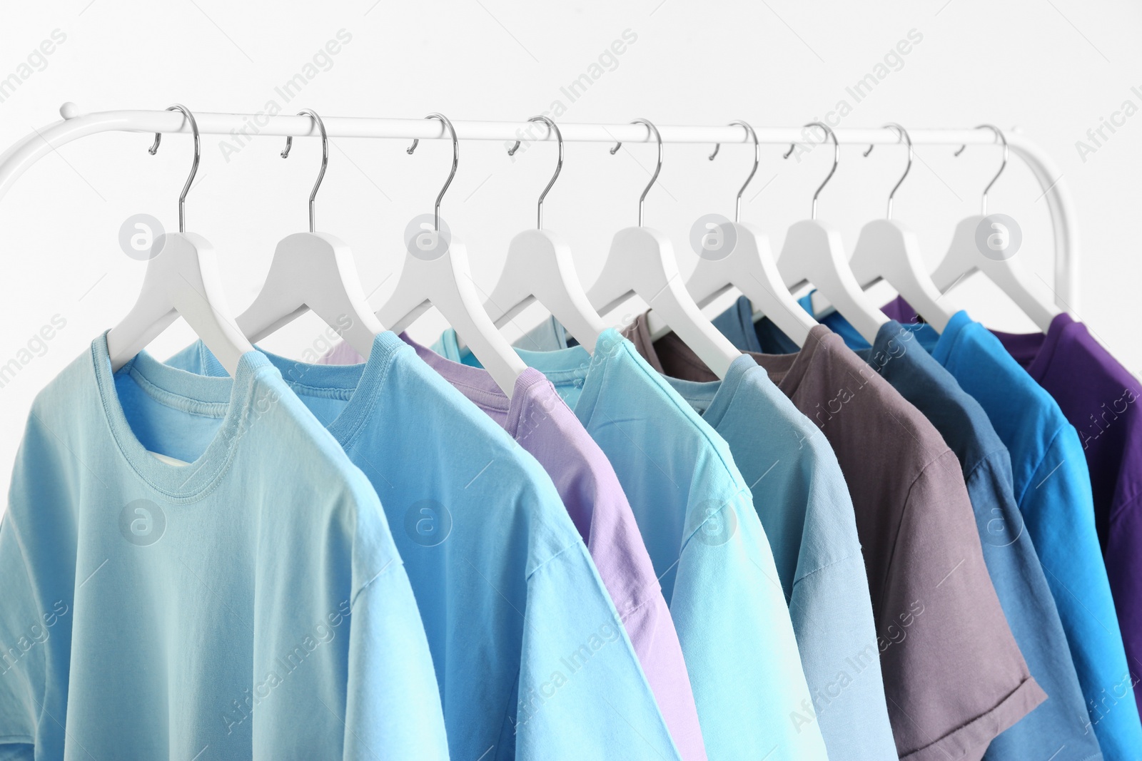 Photo of Men's clothes hanging on wardrobe rack against white background