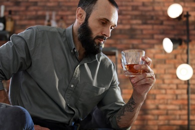 Handsome man holding glass of whiskey indoors