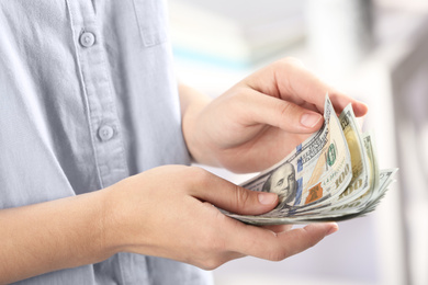 Woman counting money on blurred background, closeup