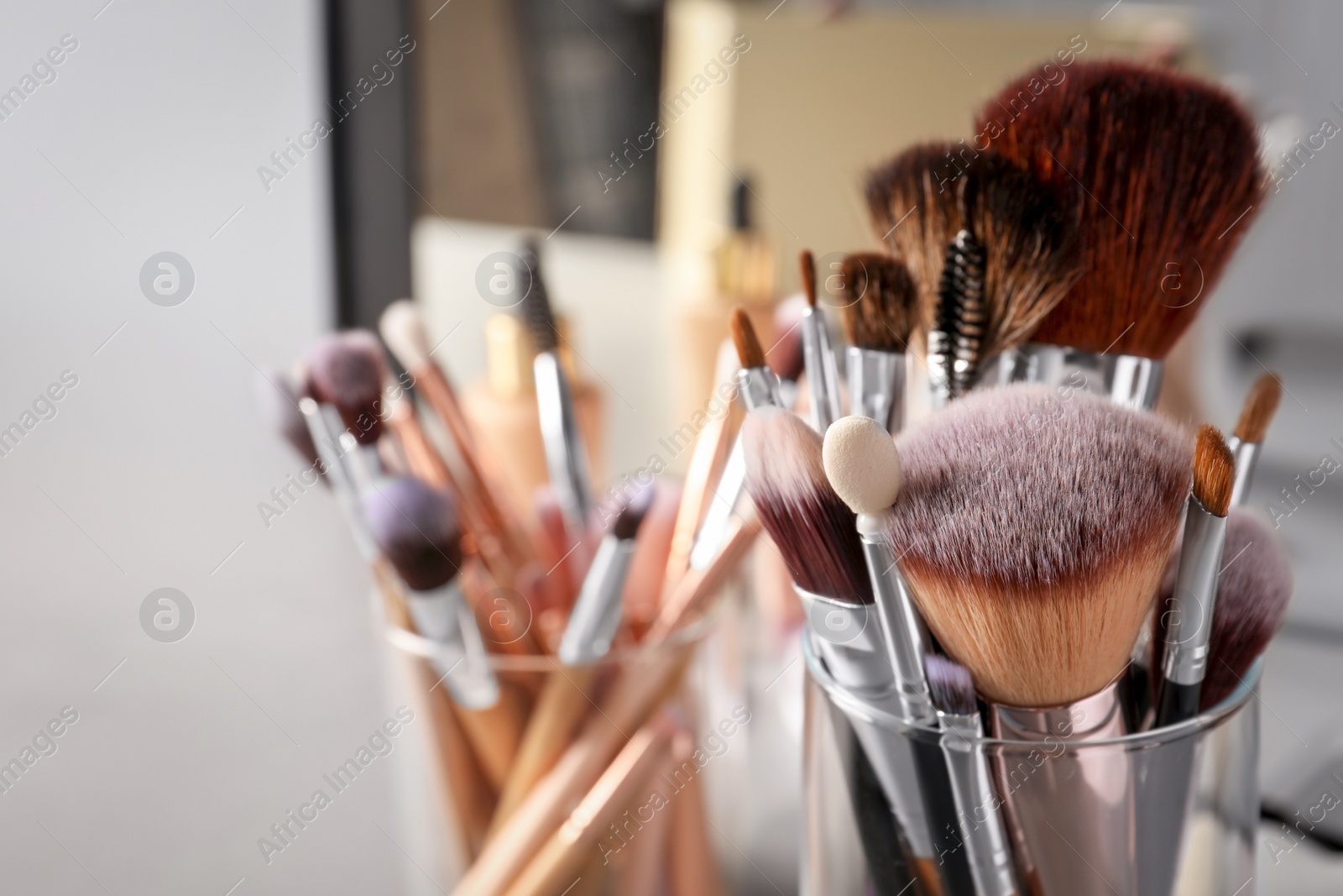 Photo of Set of professional makeup brushes near mirror, closeup