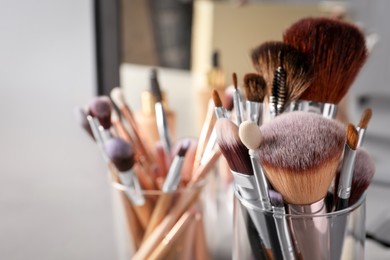 Set of professional makeup brushes near mirror, closeup