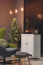 Photo of Beautiful room interior with decorated Christmas tree and white cabinet