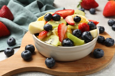 Photo of Tasty fruit salad in bowl and ingredients on gray table, closeup