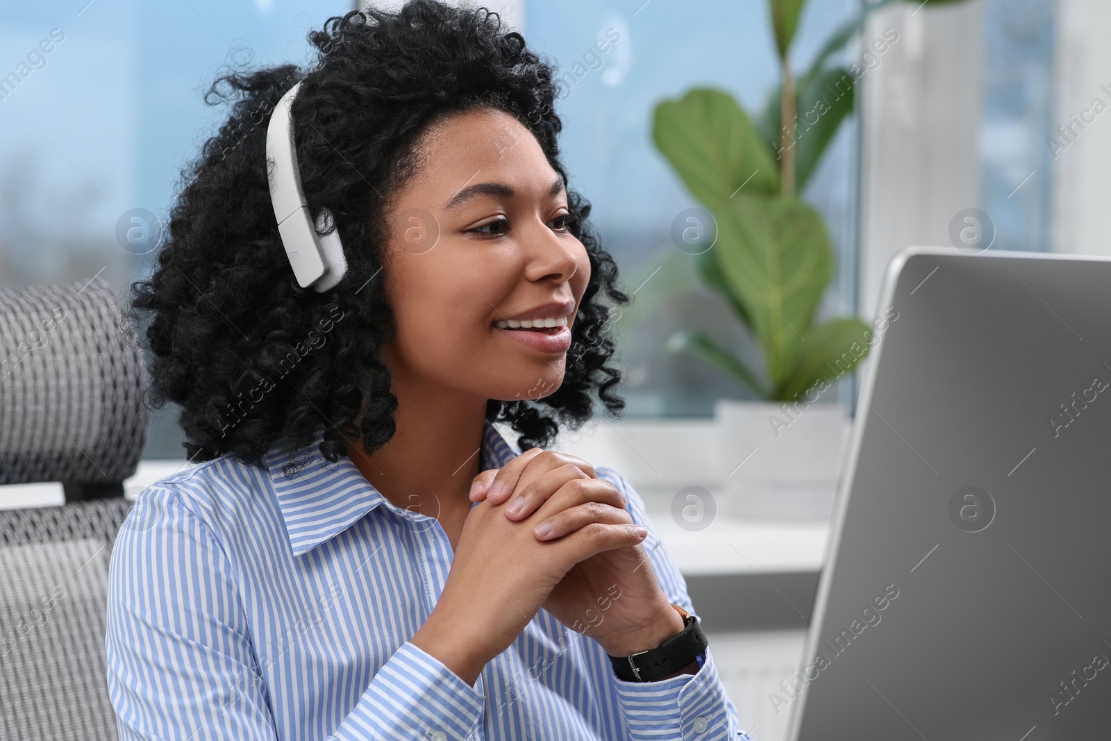 Photo of Young woman with headphones working on computer in office