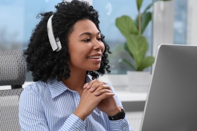 Young woman with headphones working on computer in office