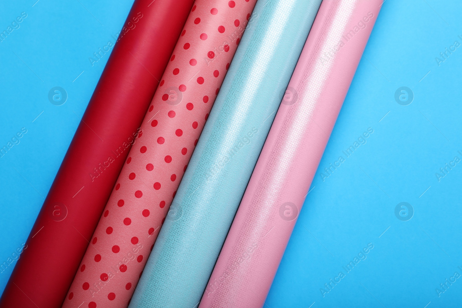 Photo of Rolls of wrapping papers on light blue background, flat lay. Space for text