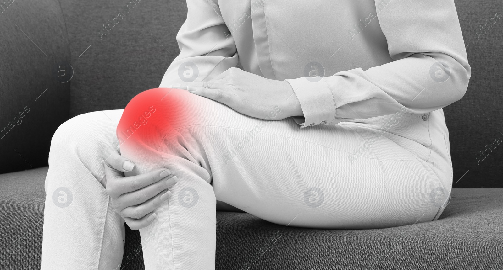 Image of Woman suffering from pain in knee on sofa, closeup. Black and white effect. Banner design