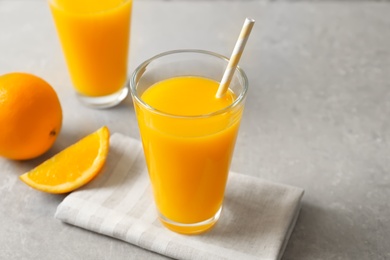 Glasses of orange juice and fresh fruits on light background