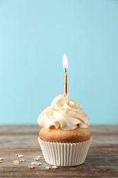 Photo of Delicious birthday cupcake with burning candle on color background