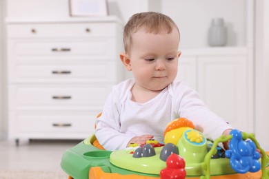 Portrait of cute baby with toy walker at home, space for text. Learning to walk