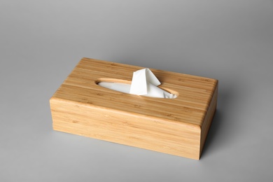 Wooden napkin holder with paper serviettes on gray background