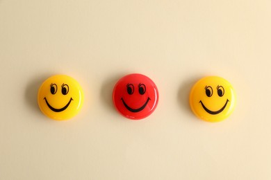 Photo of Choice concept. Red and yellow magnets with happy emoticons on beige background, flat lay