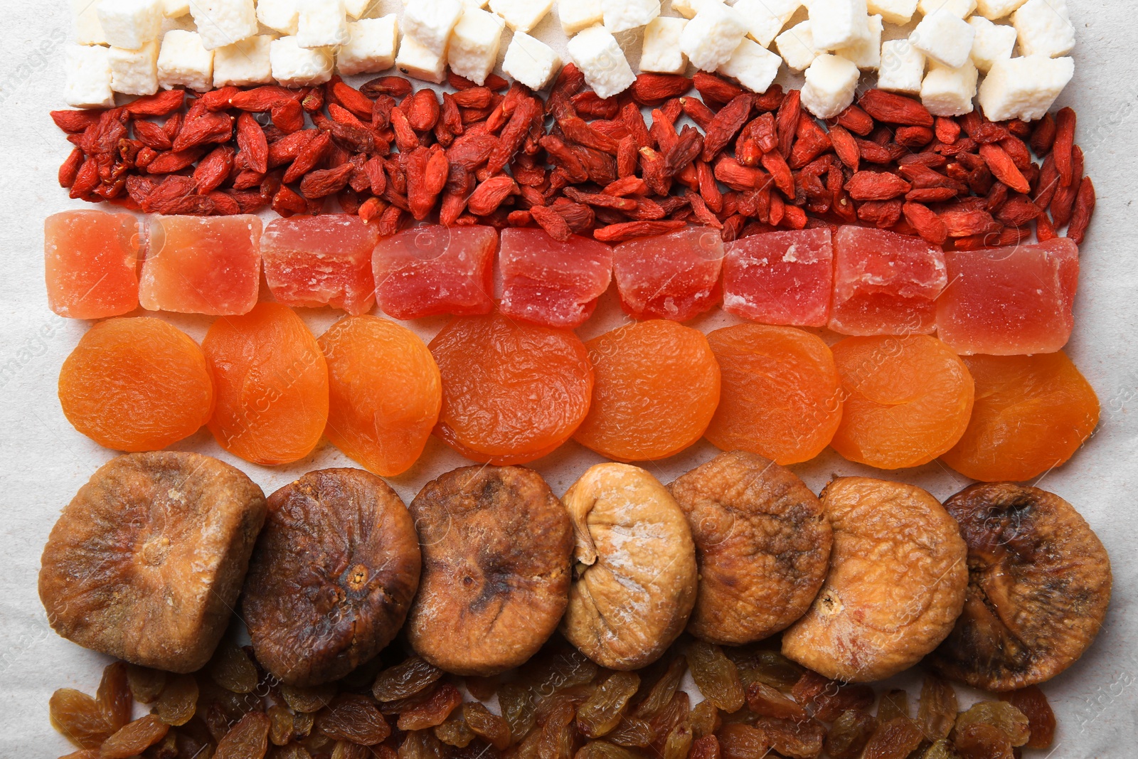 Photo of Different tasty dried fruits on paper, flat lay