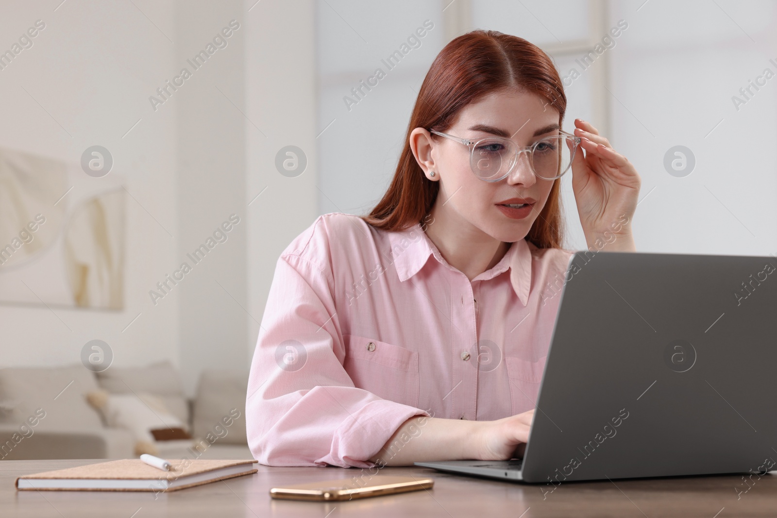 Photo of Beautiful woman using laptop at wooden table in room