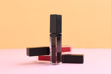 Photo of Many different lip glosses on color background