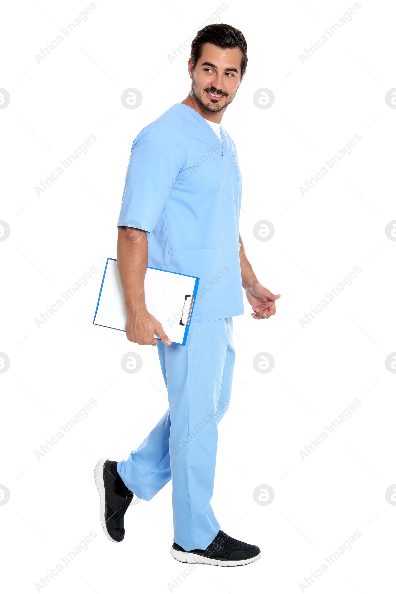 Photo of Young male doctor with clipboard walking on white background. Medical service