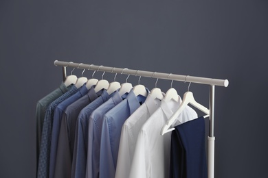 Wardrobe rack with men's clothes against grey background