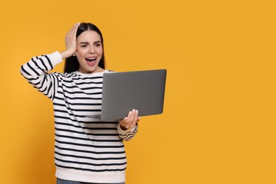 Shocked woman with laptop on orange background, space for text