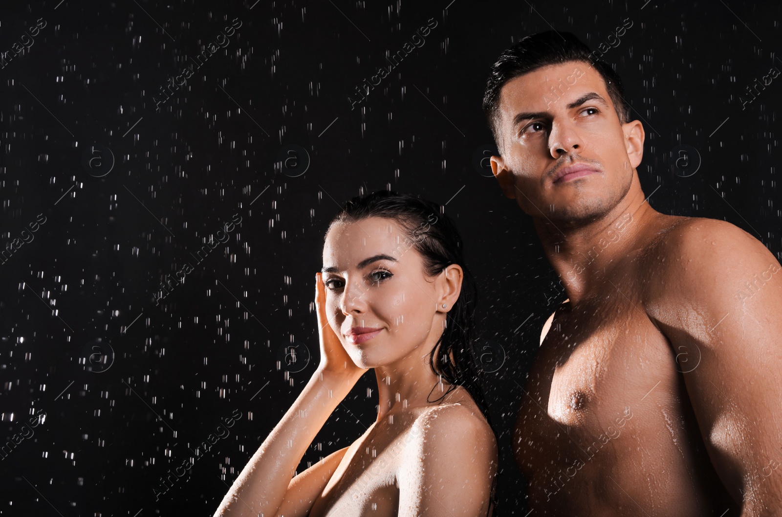 Photo of Couple taking shower against black background. Woman washing hair