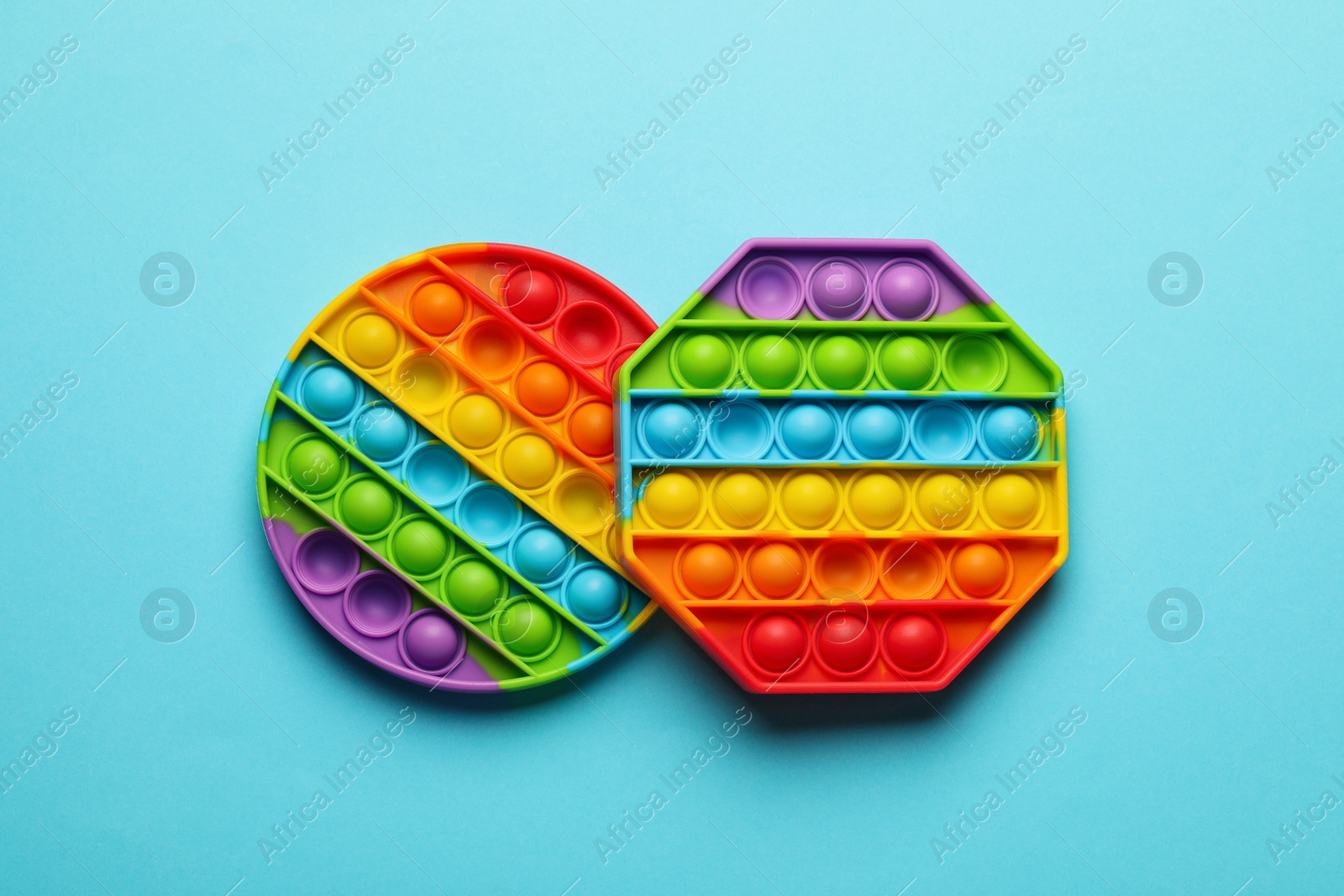 Photo of Rainbow pop it fidget toys on light blue background, flat lay