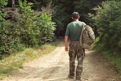 Tourist with backpack on path walking to forest. Camping season