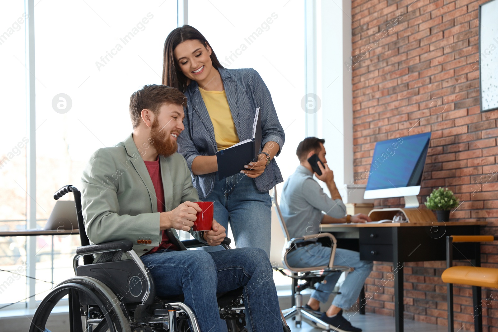 Photo of Young man in wheelchair with colleagues at office