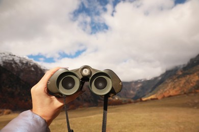 Boy holding binoculars in beautiful mountains, closeup. Space for text