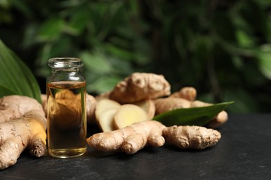 Photo of Ginger essential oil in bottle on dark table. Space for text
