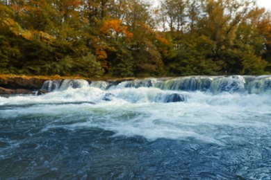 Blurred view of river with rapids near forest