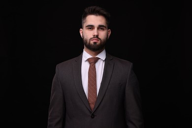 Handsome businessman in suit and necktie on black background