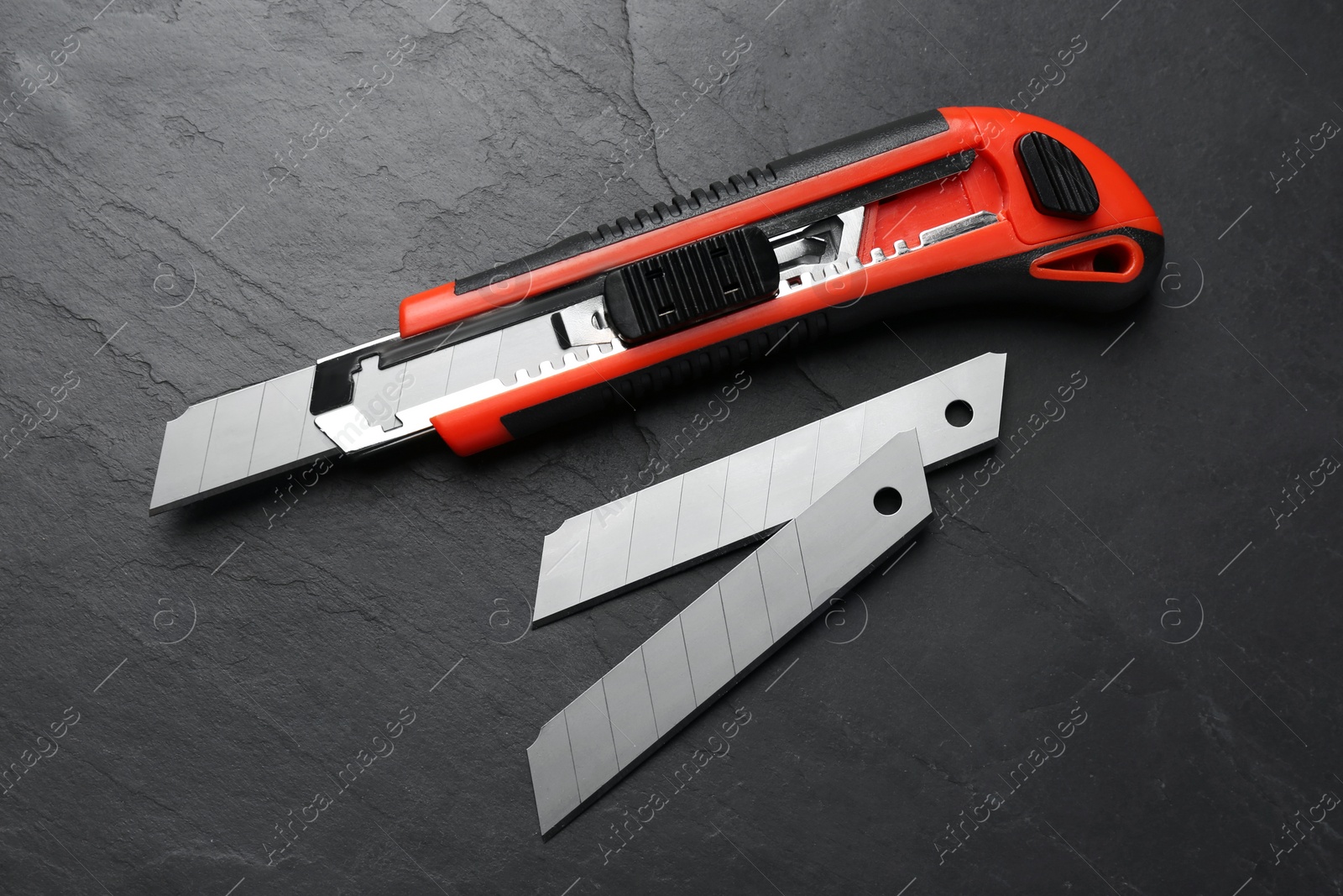 Photo of Utility knife and blades on black table, flat lay