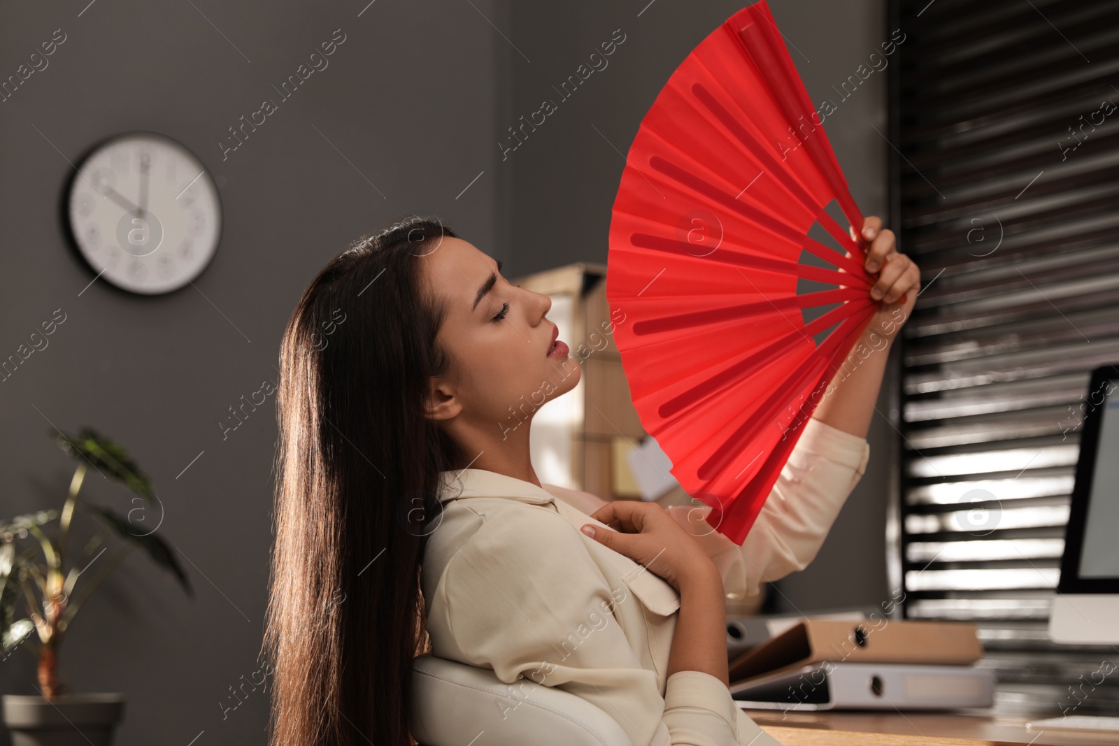 Photo of Woman with hand fan suffering from heat at home. Summer season