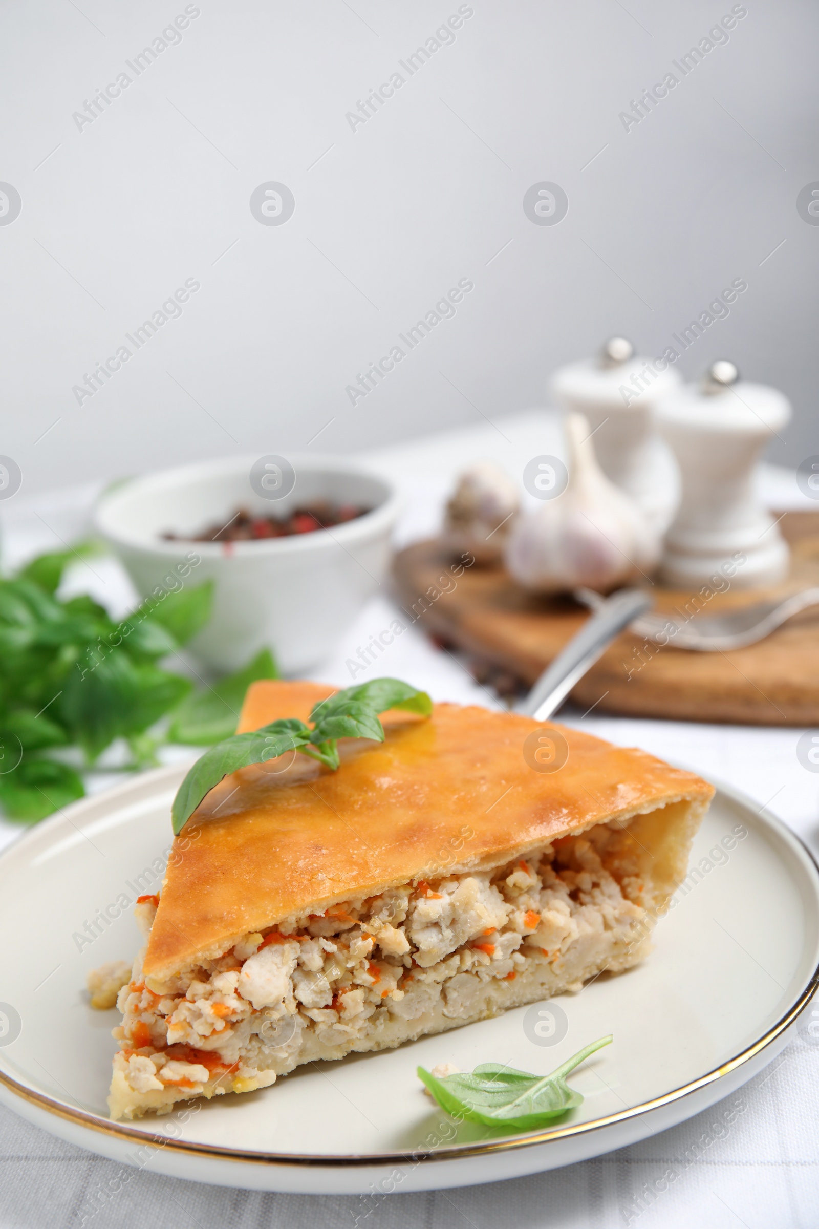 Photo of Slice of delicious meat pie with basil on table, space for text