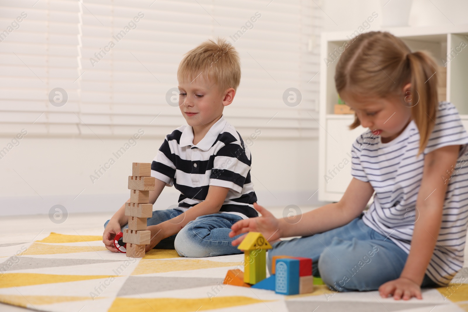 Photo of Little children playing with building blocks indoors. Wooden toys