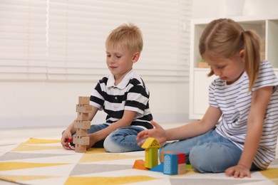 Little children playing with building blocks indoors. Wooden toys
