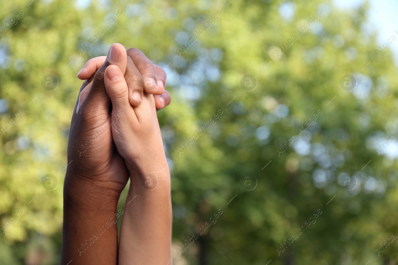 Photo of Woman and African American man holding hands outdoors, closeup