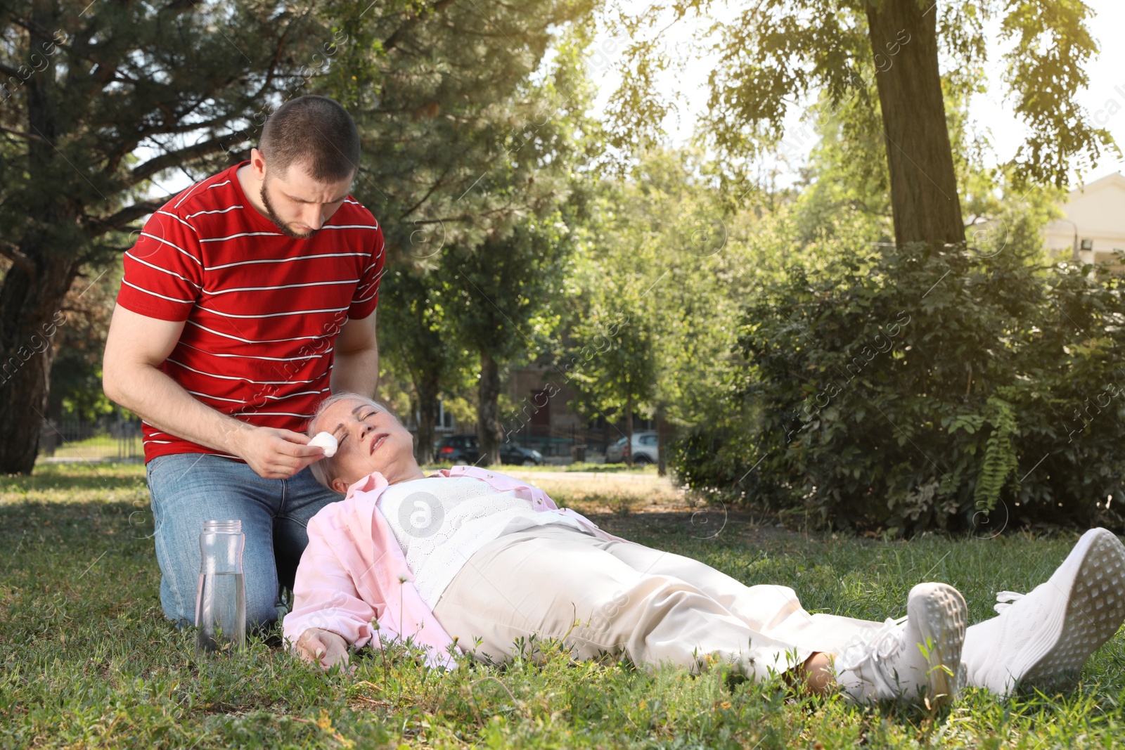 Photo of Man helping mature woman in park. Suffering from heat stroke