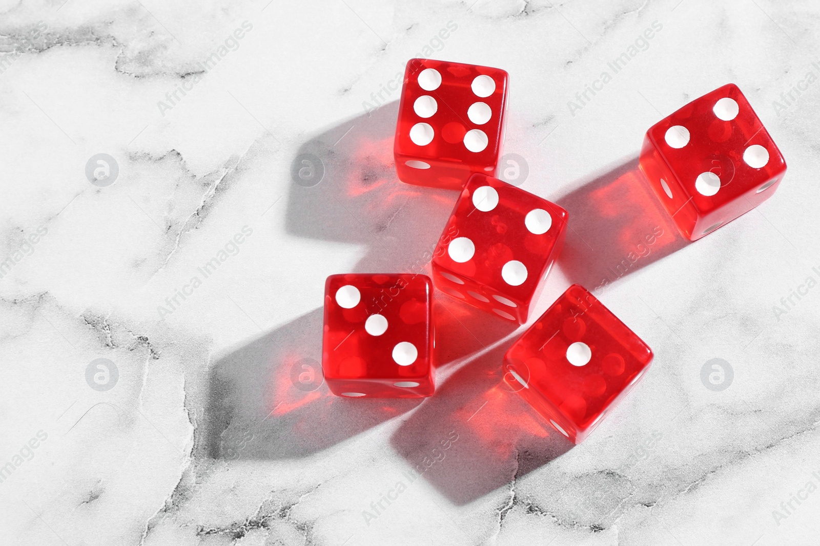 Photo of Many red game dices on white marble table, flat lay