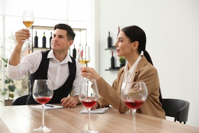 Sommeliers tasting different sorts of wine at table indoors