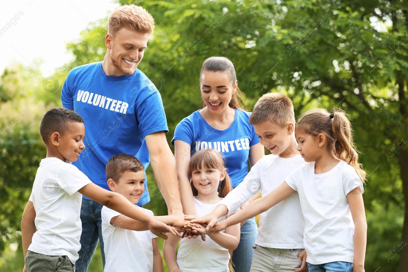 Photo of Group of kids joining hands with volunteers in park