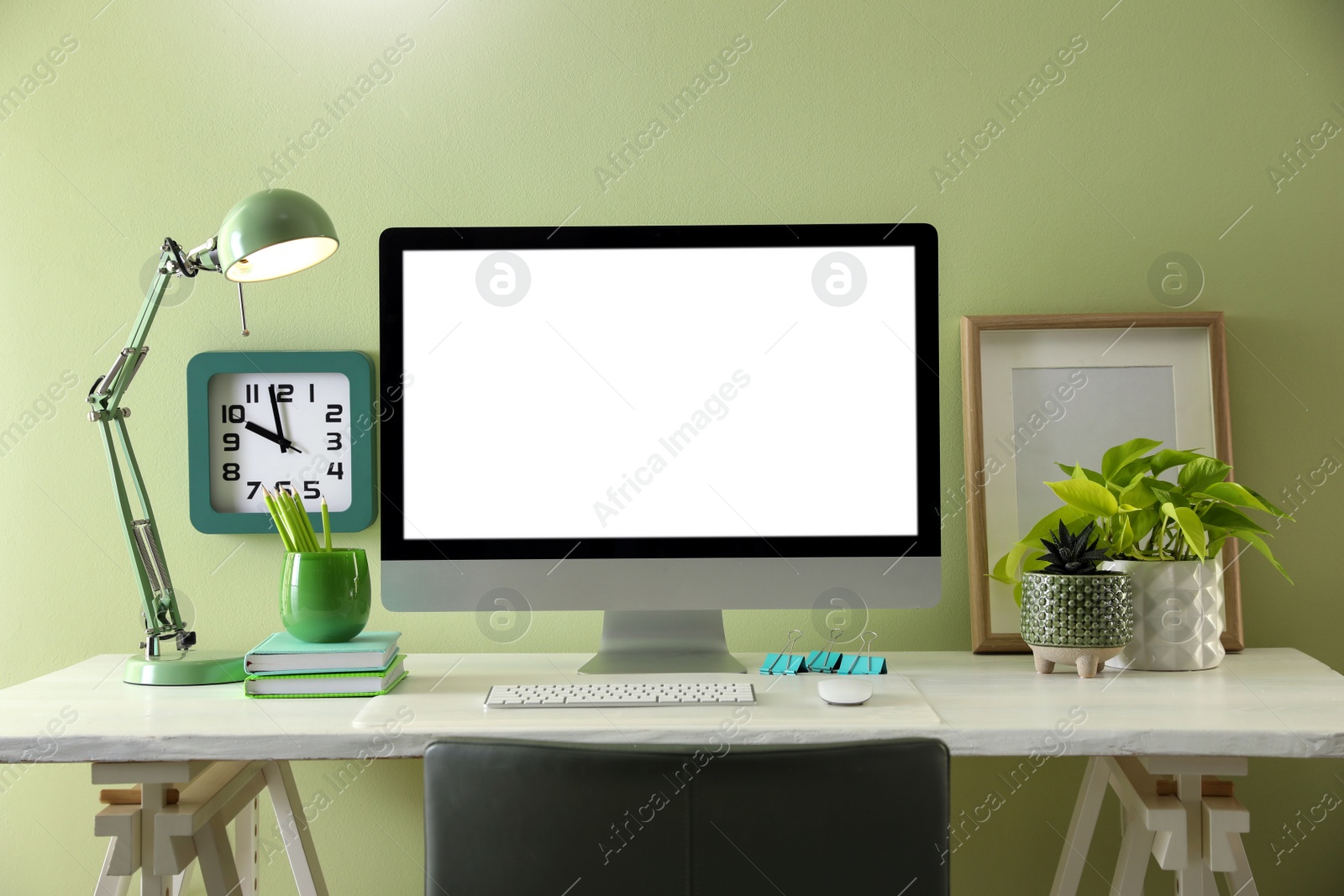 Photo of Stylish workplace with modern computer near light green wall indoors. Space for text