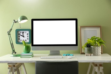 Photo of Stylish workplace with modern computer near light green wall indoors. Space for text