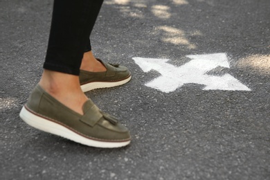 Photo of Woman standing near arrow on asphalt, closeup