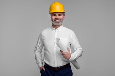 Photo of Architect in hard hat holding draft on grey background