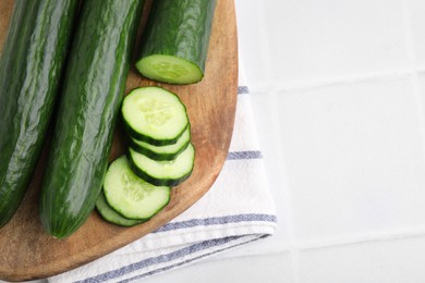 Photo of Fresh cucumbers on white tiled table, top view. Space for text