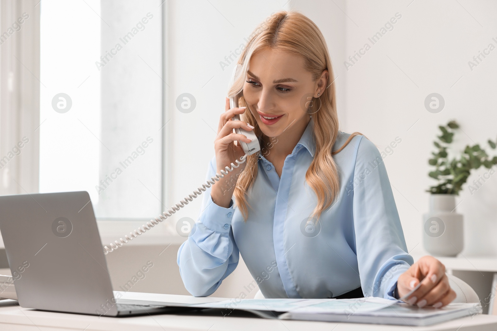 Photo of Happy secretary talking on phone in office