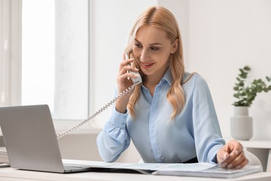 Happy secretary talking on phone in office