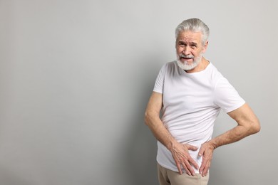 Photo of Arthritis symptoms. Man suffering from hip joint pain on gray background, space for text