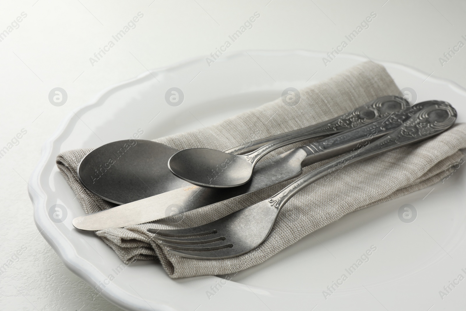 Photo of Stylish setting with cutlery, napkin and plate on white table, closeup